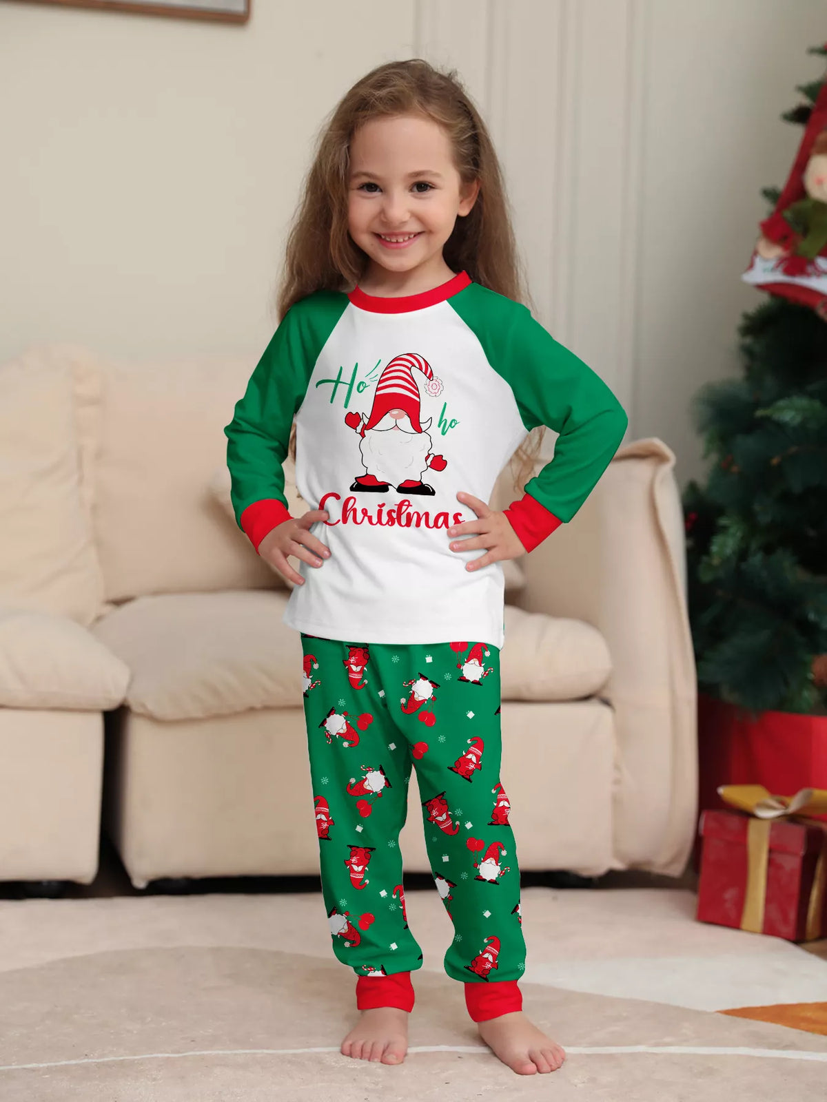 Child wearing the white Christmas graphic top and green printed pajama pants.