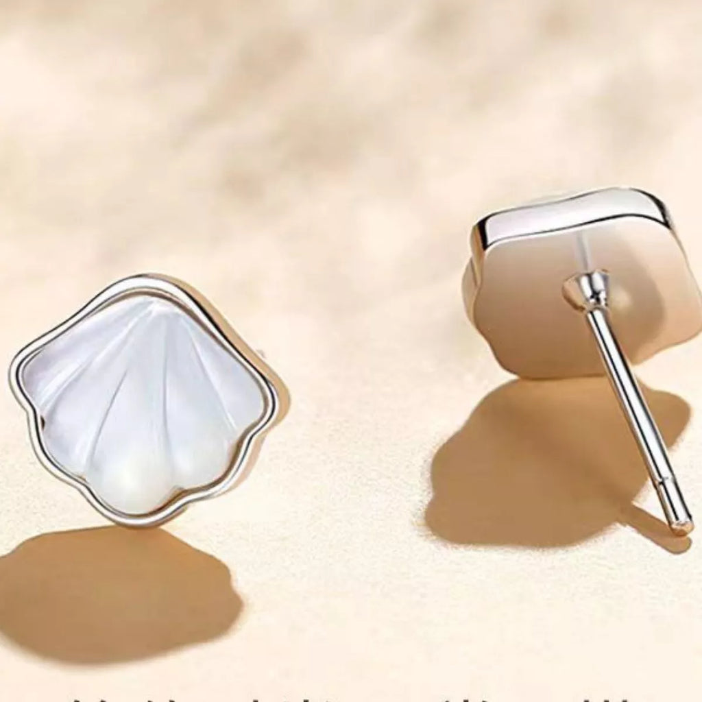 Silver-tone shell-shaped stud earrings with white centers — detail view