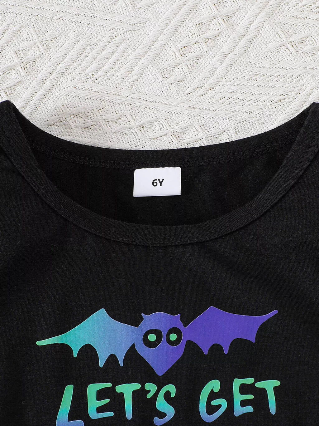 Close-up of the black dress neckline and colorful bat graphic.