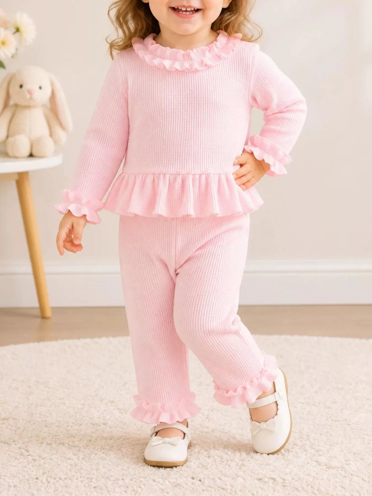 Child wearing a pink long-sleeve ruffle-trim top and matching pants.