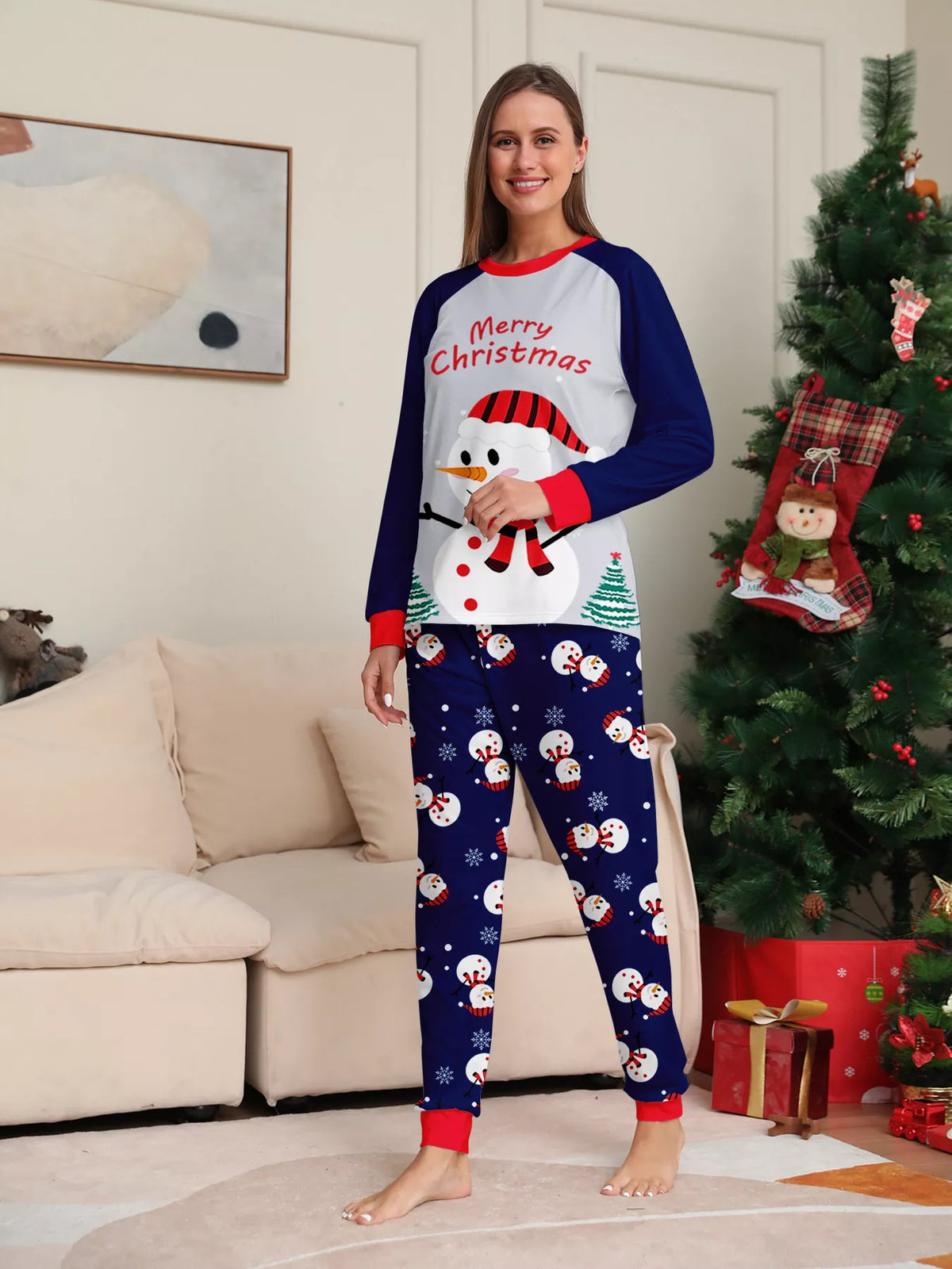 Woman modeling a white snowman Christmas top with navy sleeves and navy snowman-print pants.