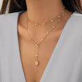 Gold-tone pearl-like station necklace with coin pendant