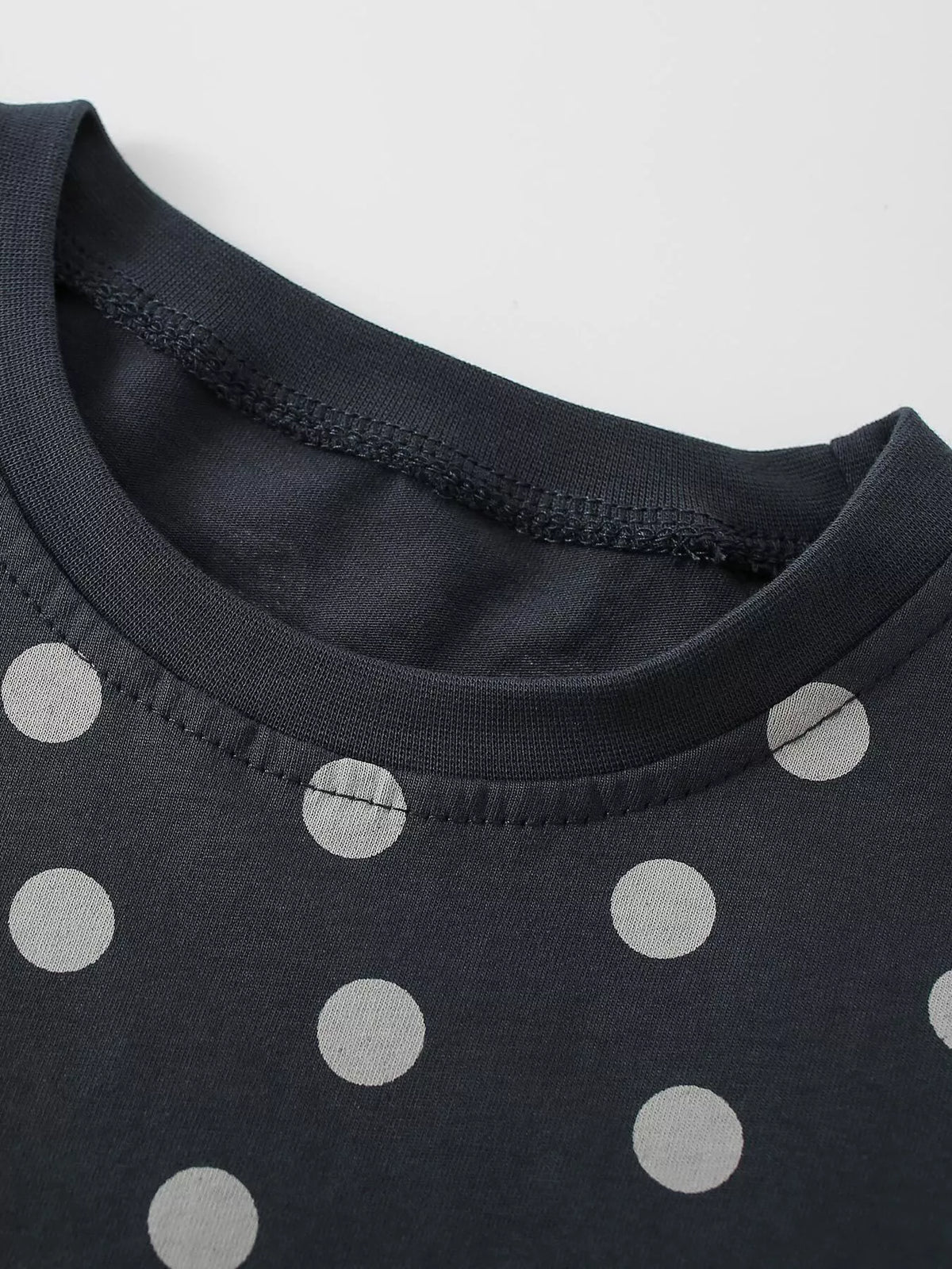 Close-up of the dark polka-dot top's crew neckline.