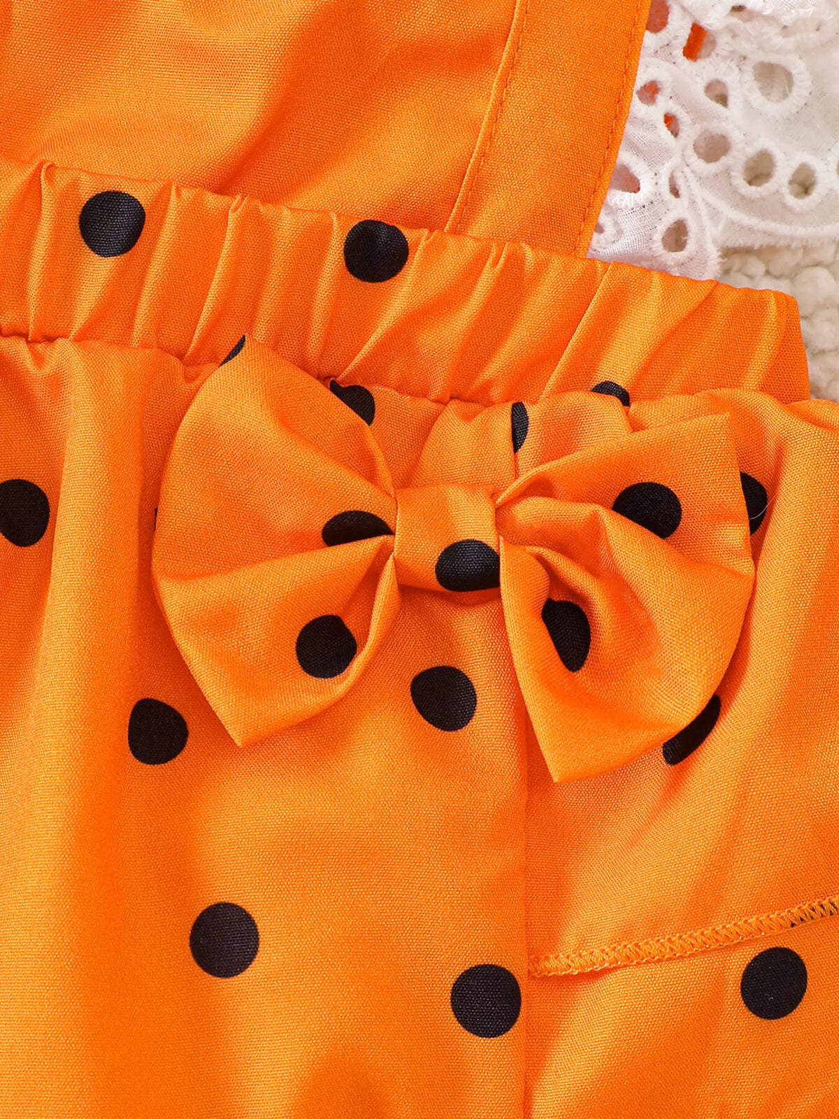 Close-up of the orange polka-dot romper's waistband and bow.
