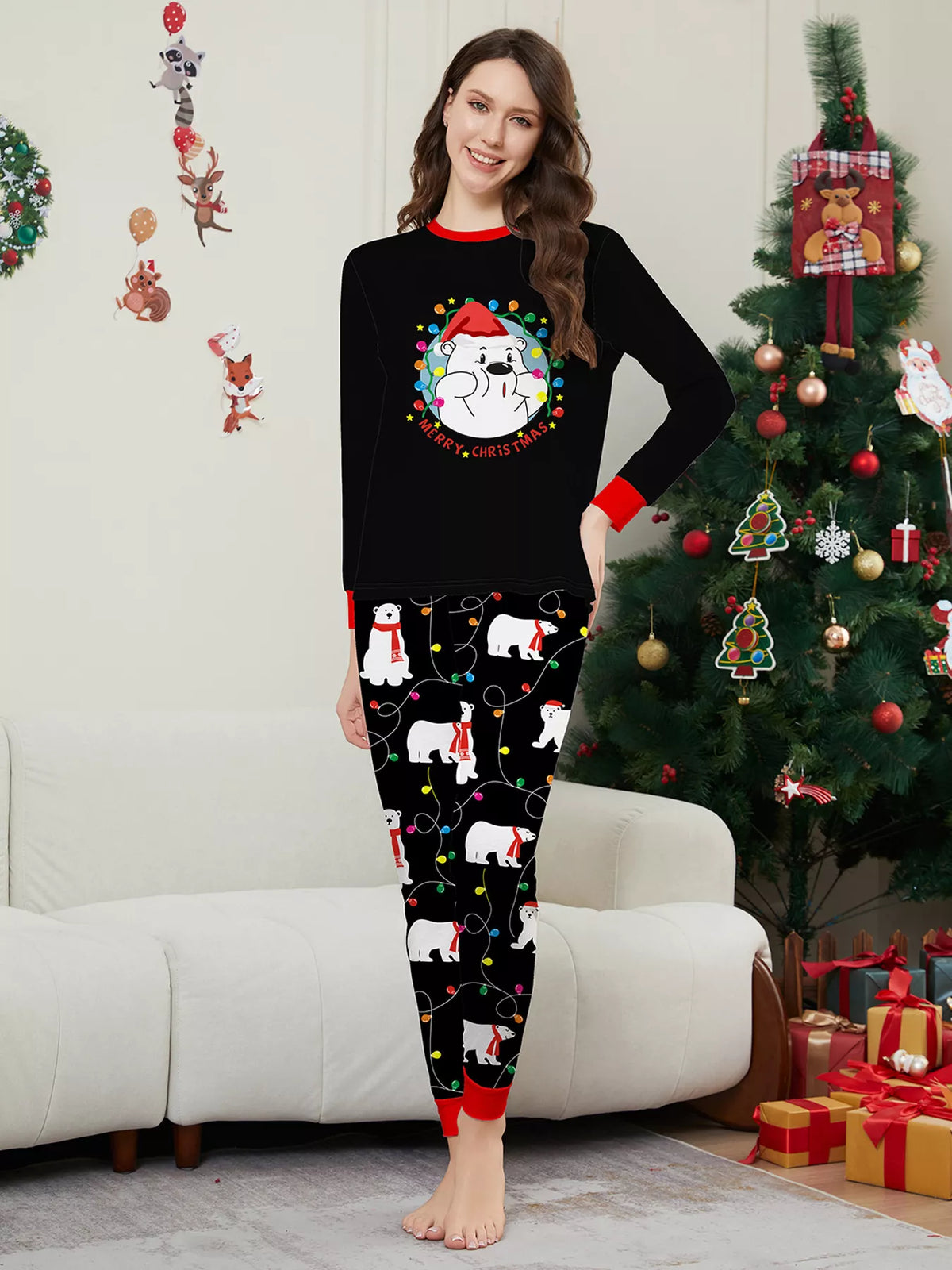 Woman modeling a black Christmas graphic top and black polar-bear-print pajama pants.