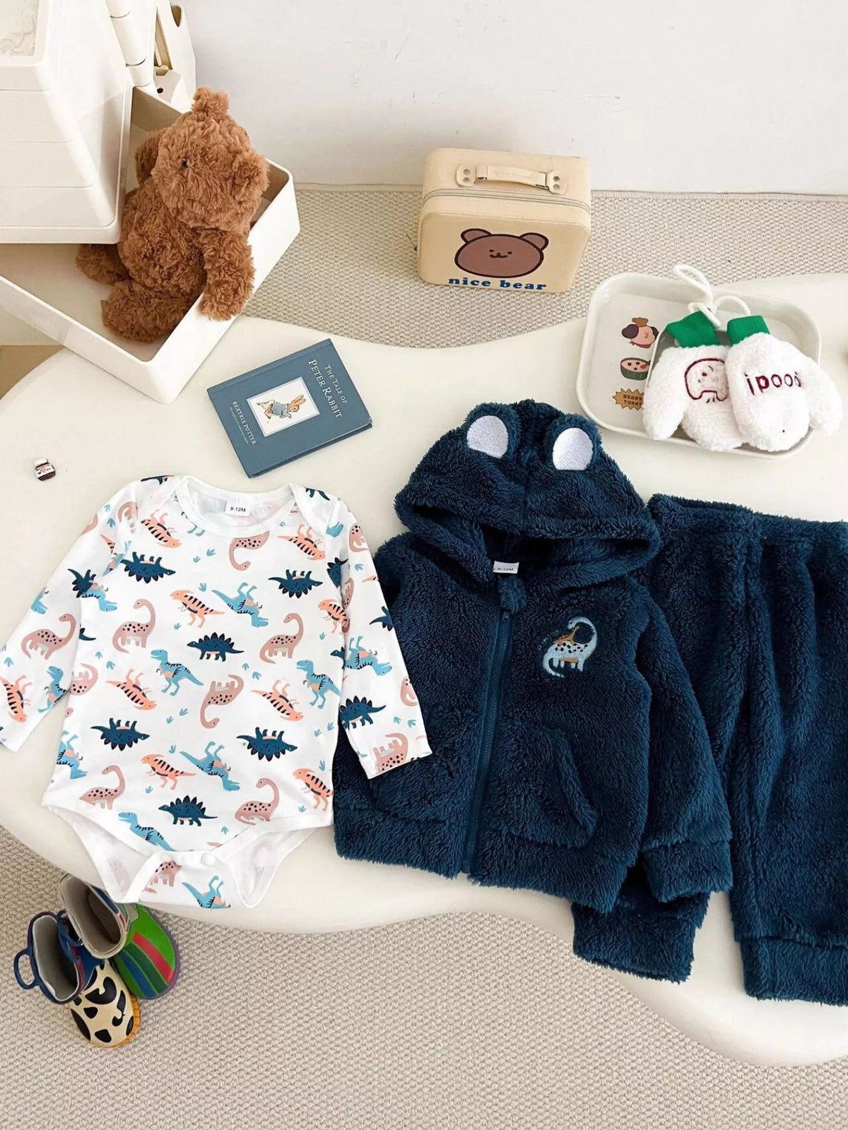 Children’s navy dinosaur fleece hoodie and pants with a white dinosaur-print bodysuit displayed flat