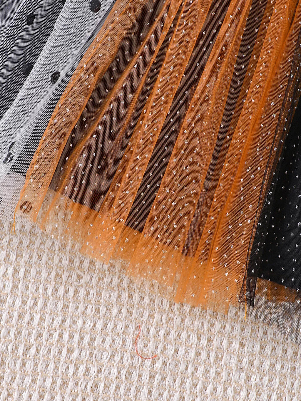 Close-up of orange, black and white dotted tulle skirt panels.
