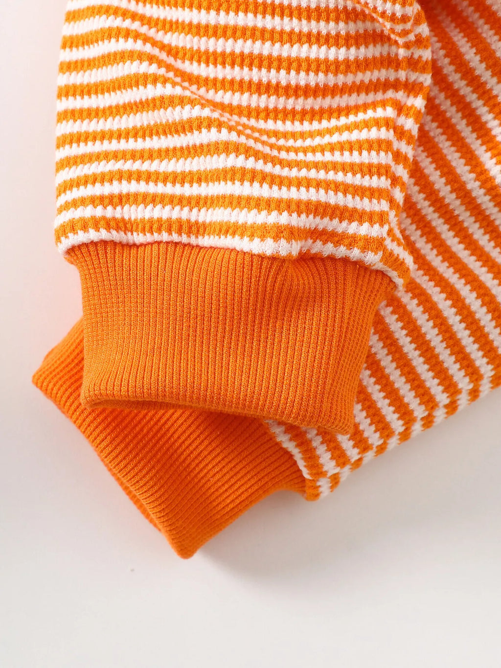 Orange ribbed cuff and striped sleeve detail