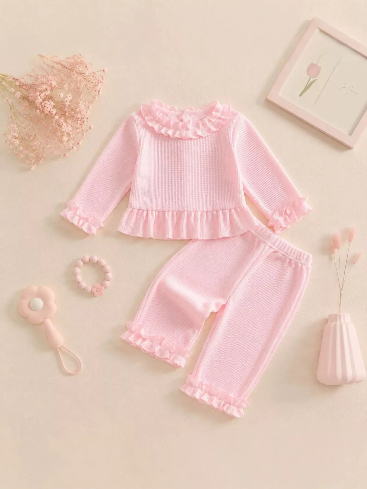 Flat lay of the pink ruffle-neck top and matching ruffle-hem pants.