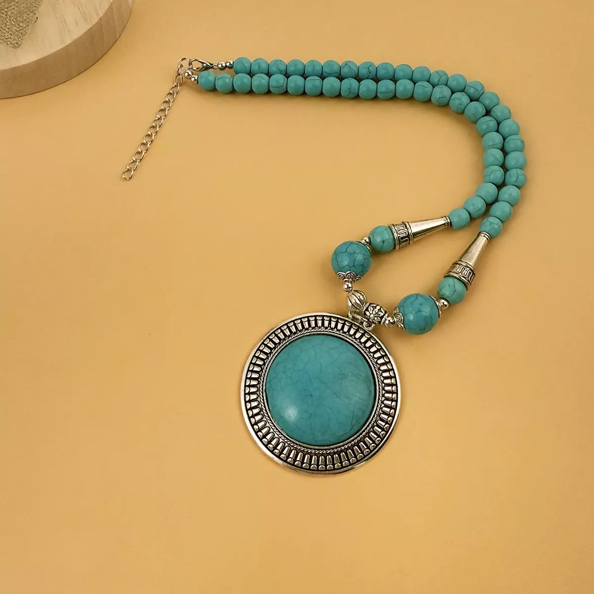 Turquoise-colored round medallion pendant necklace with large beads — detail view