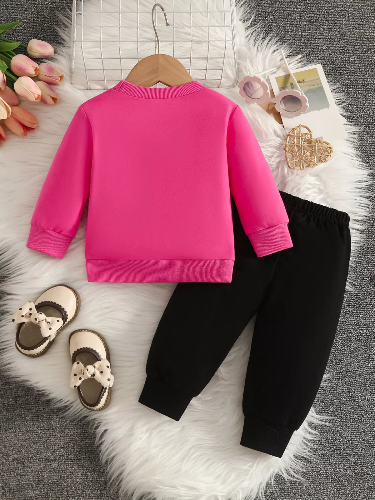 Back flat lay of the bright pink top and black pants.