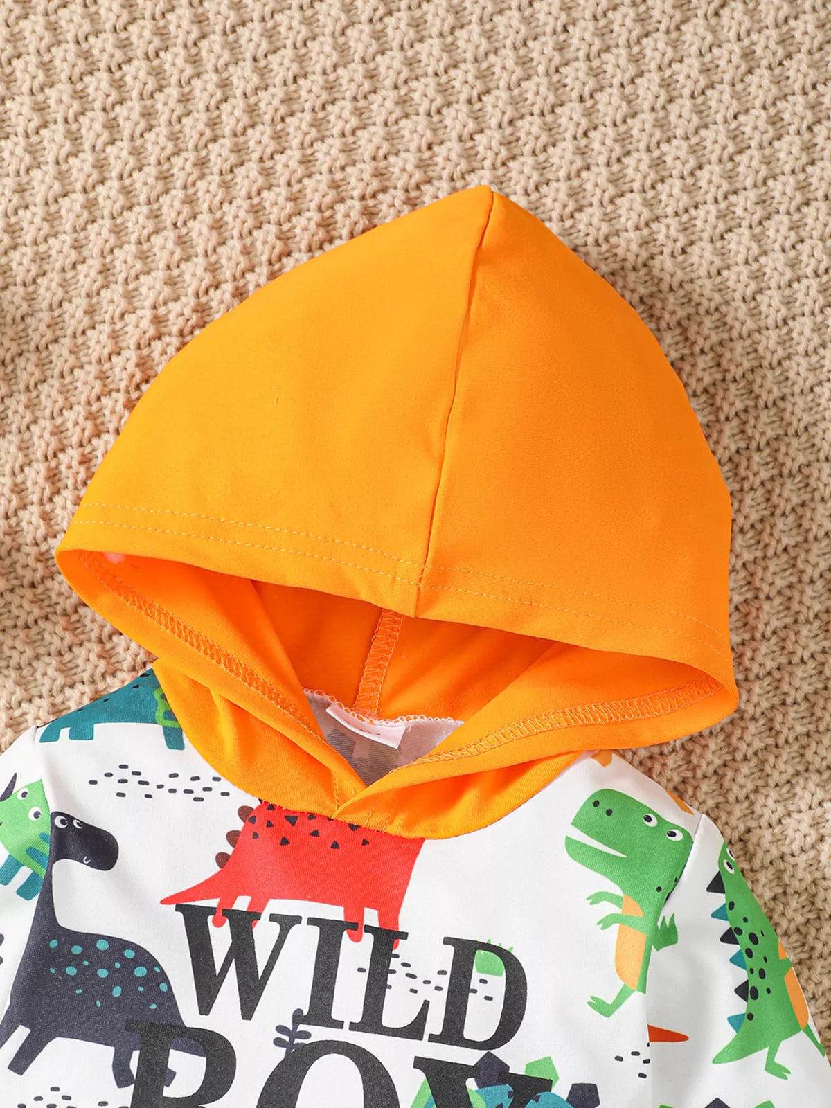 Orange hood and colorful dinosaur print on the baby bodysuit