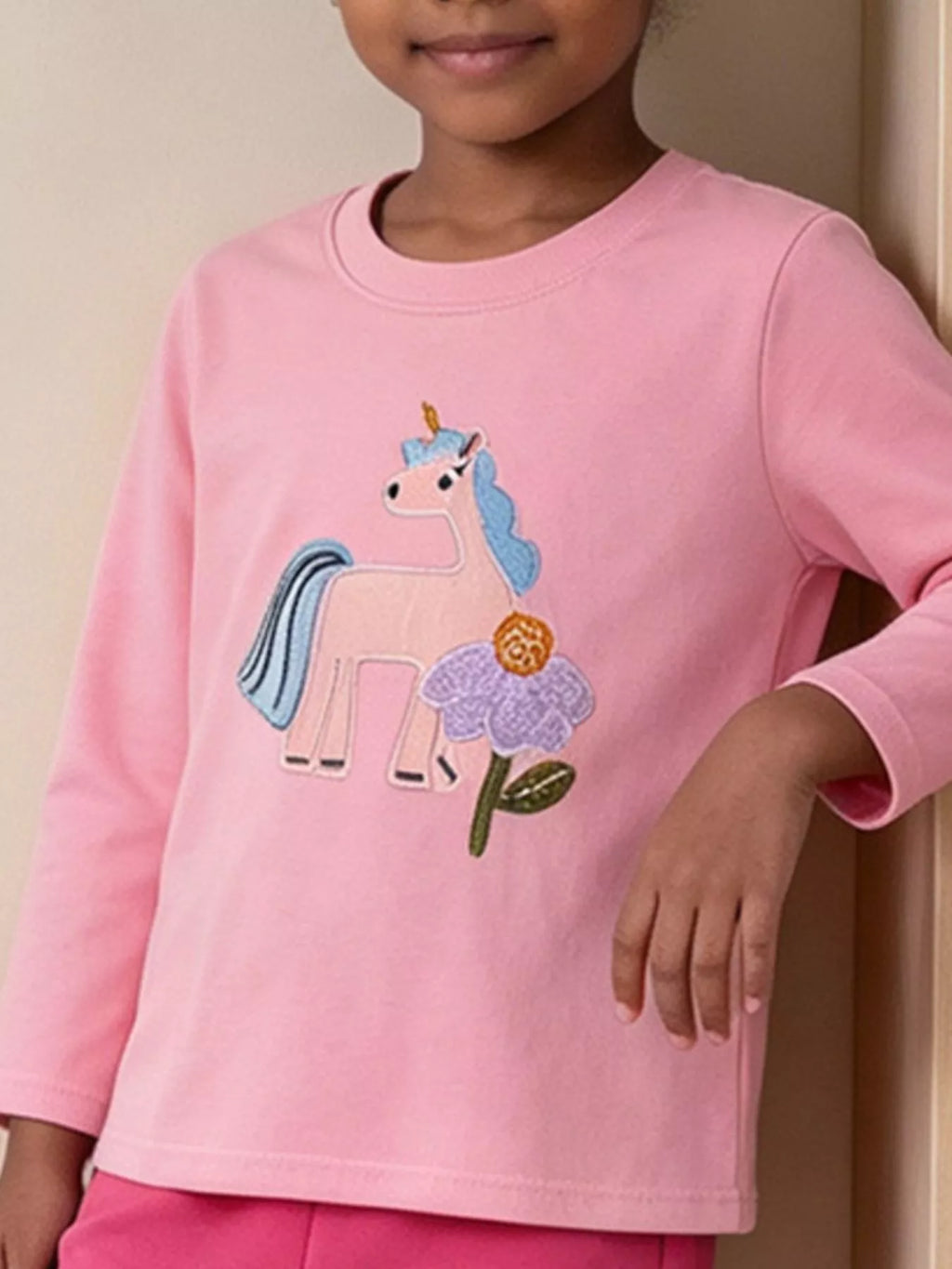 Long-sleeve children’s top with colorful embroidered graphics worn by a child