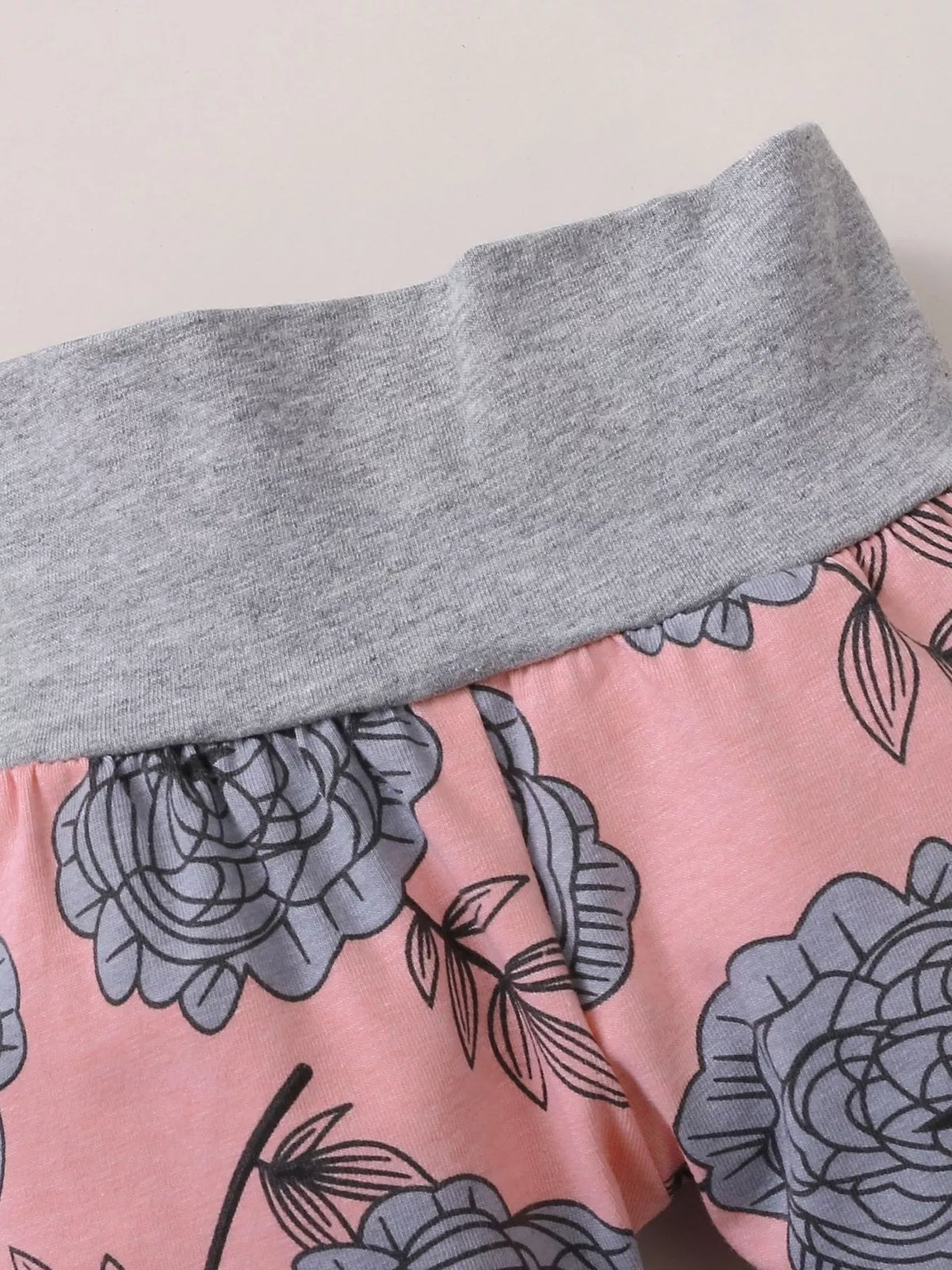 Gray waistband and dark floral print on the pink baby pants