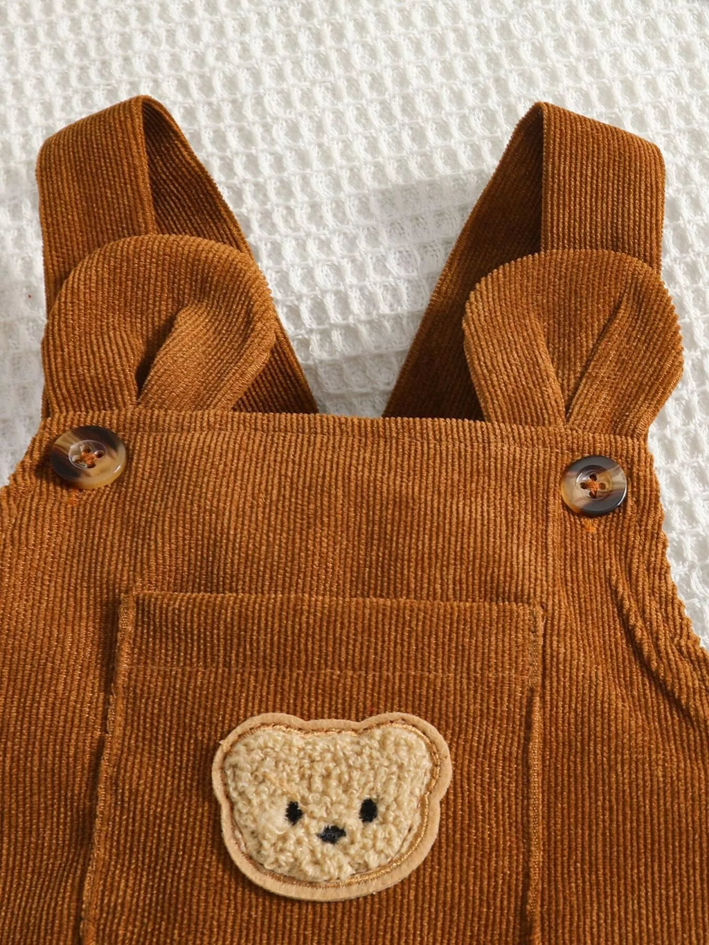 Bear-face patch and button straps on brown corduroy overalls