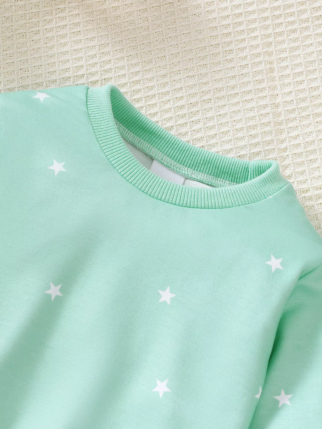 Close-up of the mint star-print sweatshirt's ribbed neckline.