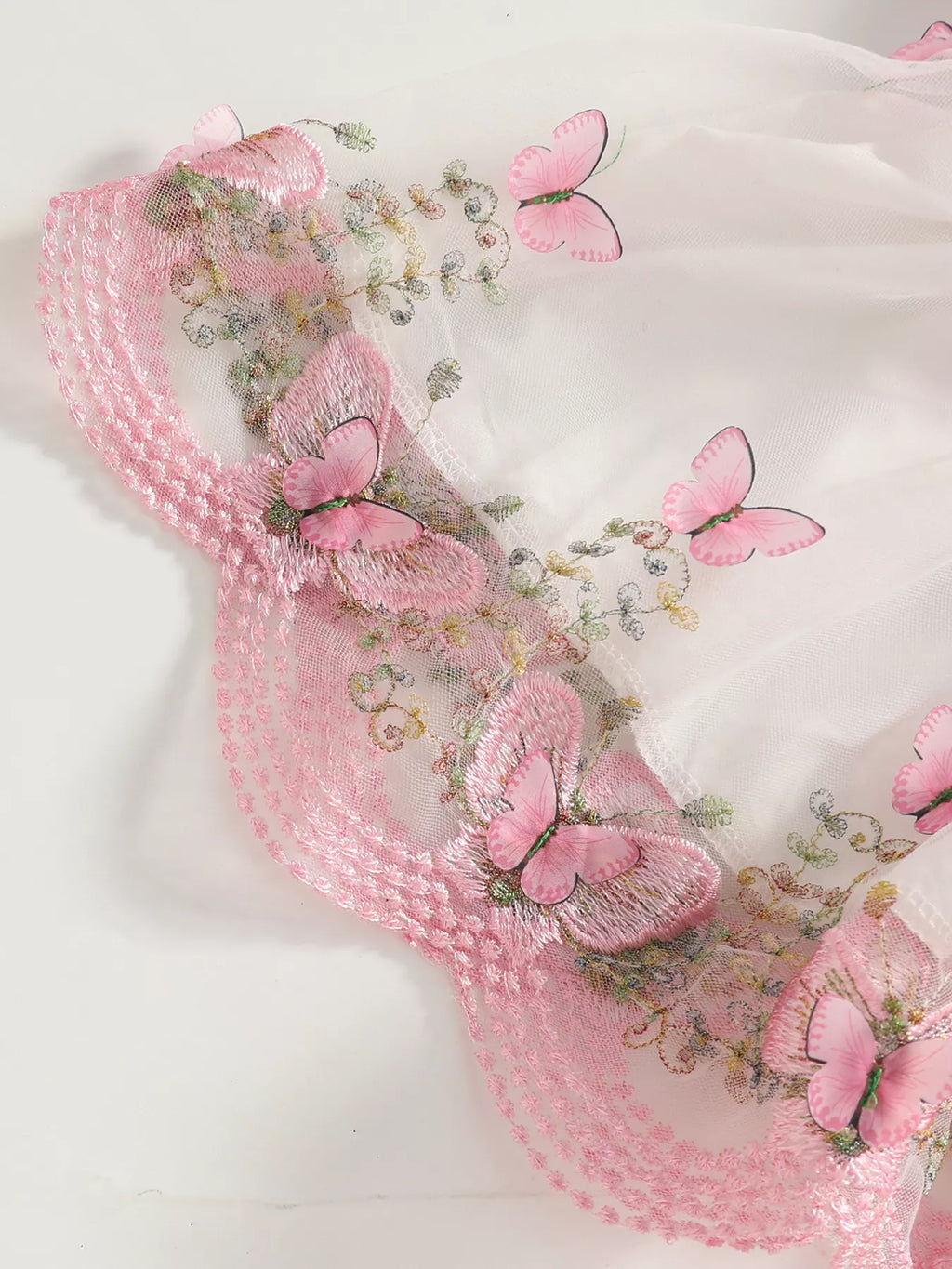 Close-up of butterfly and floral trim along the white tulle skirt's pink hem.