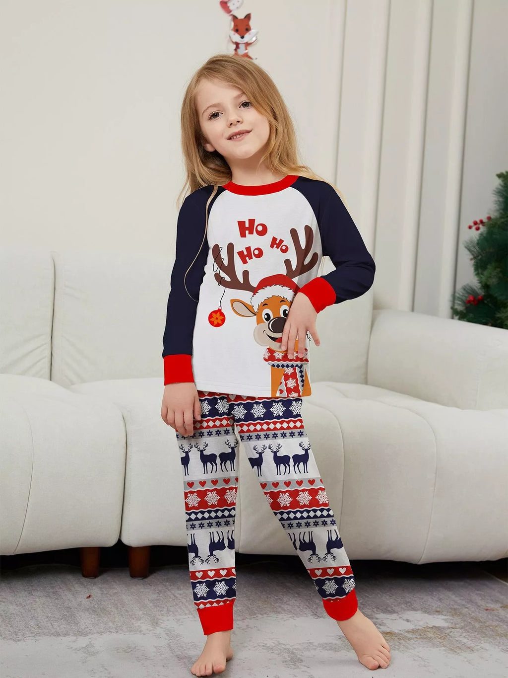 Child wearing the white reindeer Christmas top and festive striped pajama pants.