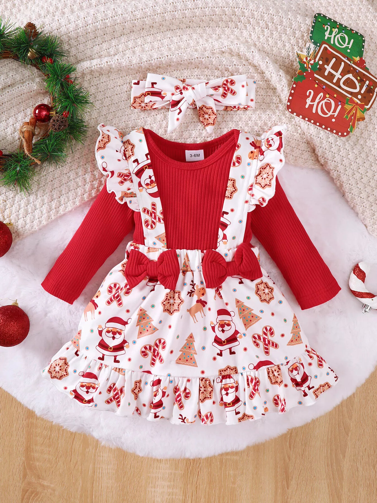 Front flat lay of a red long-sleeve bodysuit with Santa-print suspender skirt and headband.