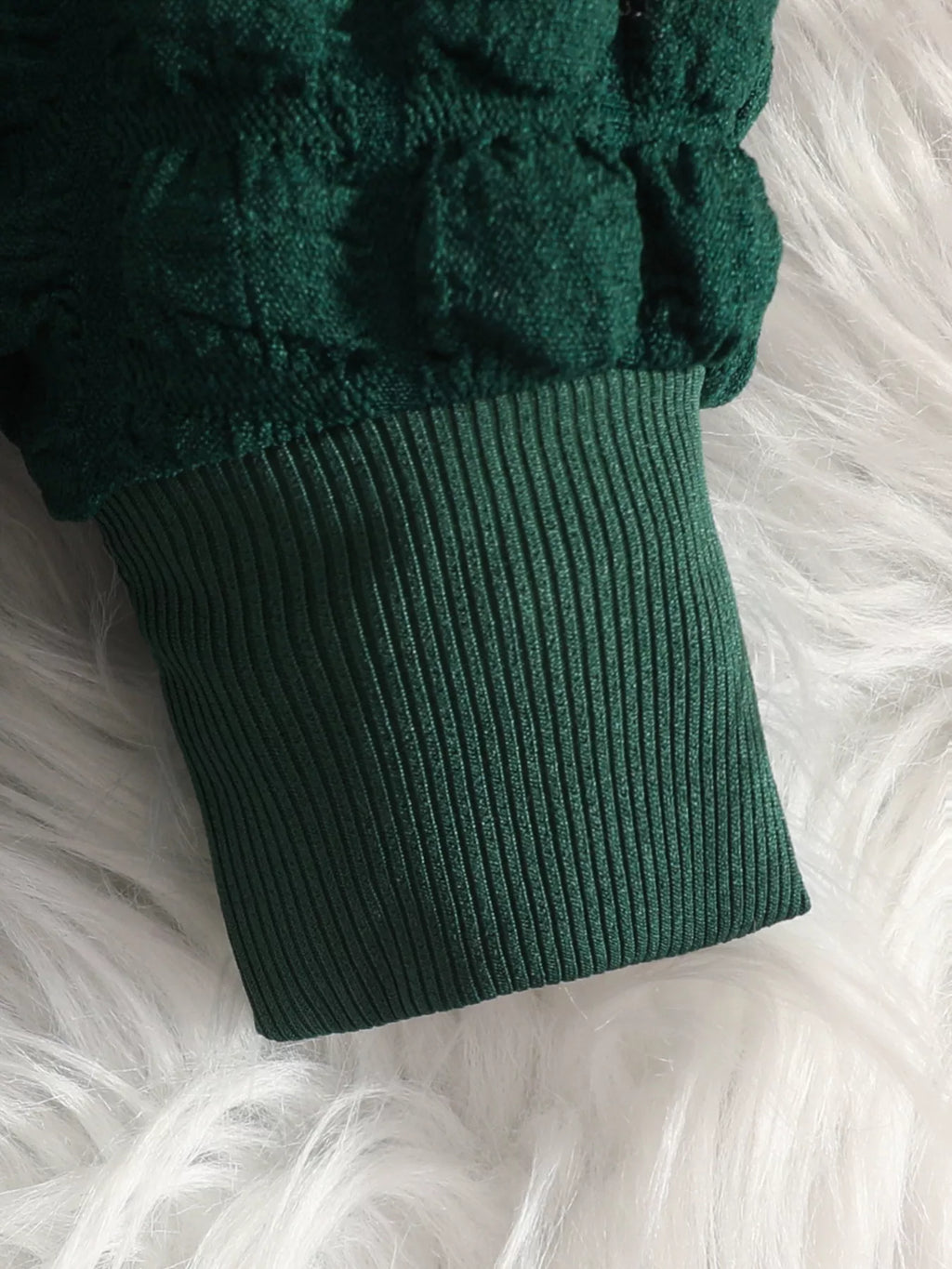 Close-up of the green top's textured sleeve and ribbed cuff.