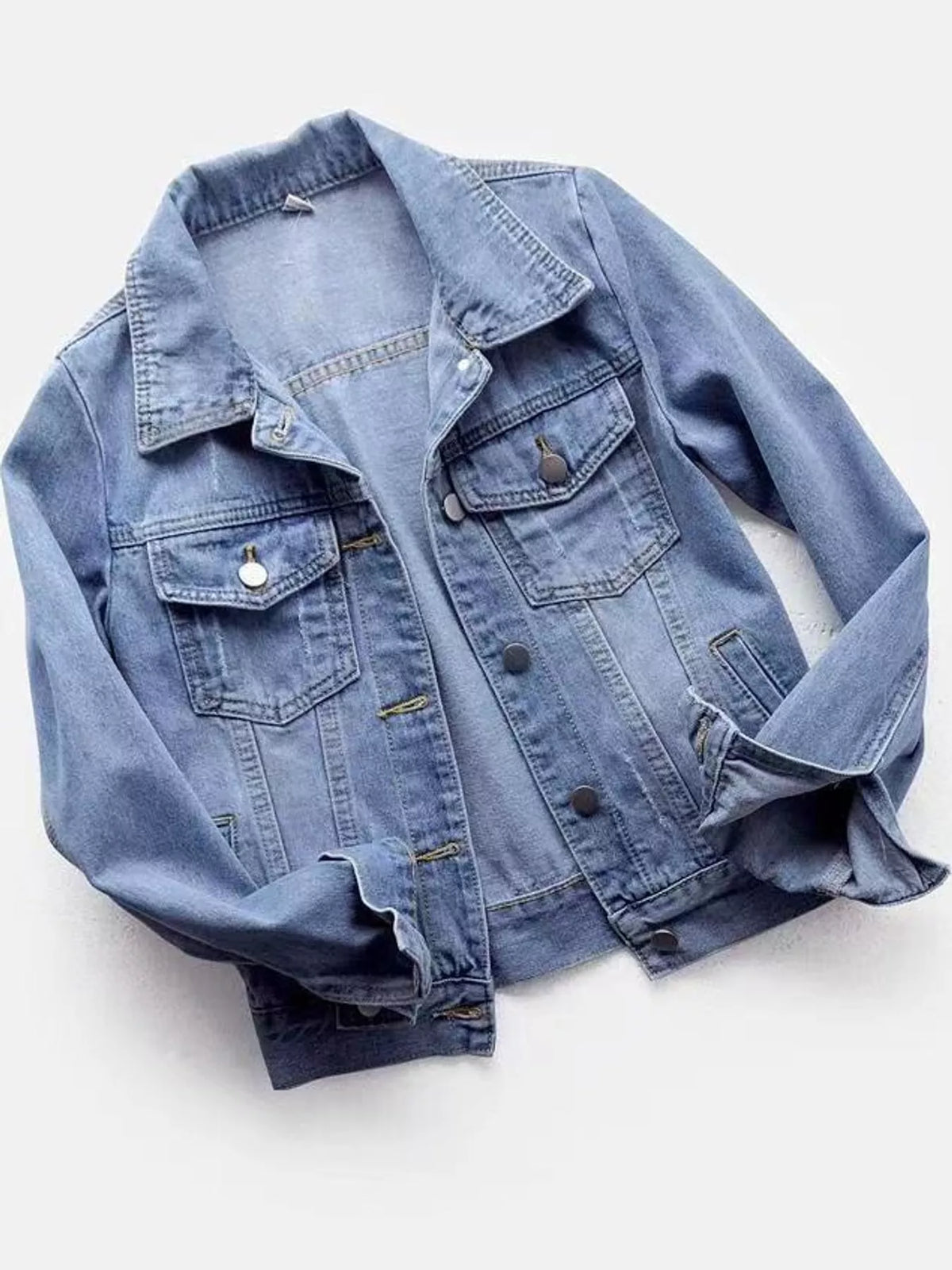 Light-wash button-front denim jacket displayed with chest pockets and rolled cuffs.