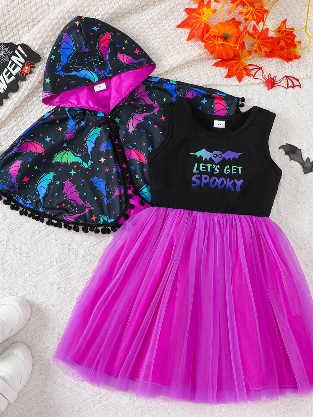 Front flat lay of the bat-print cape and black Let's Get Spooky dress with purple tulle skirt.