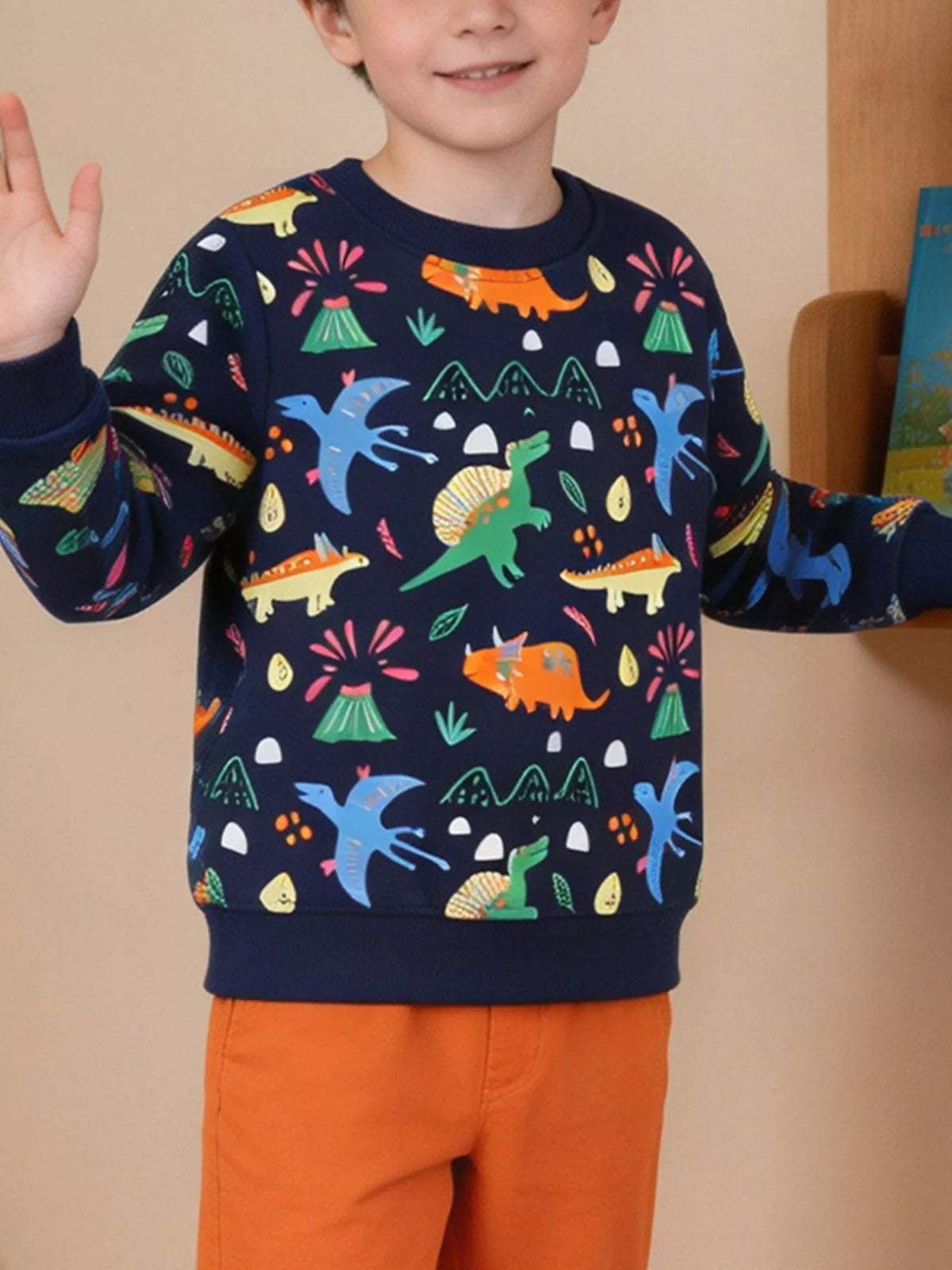 Child wearing a navy sweatshirt with colorful dinosaurs and orange pants.