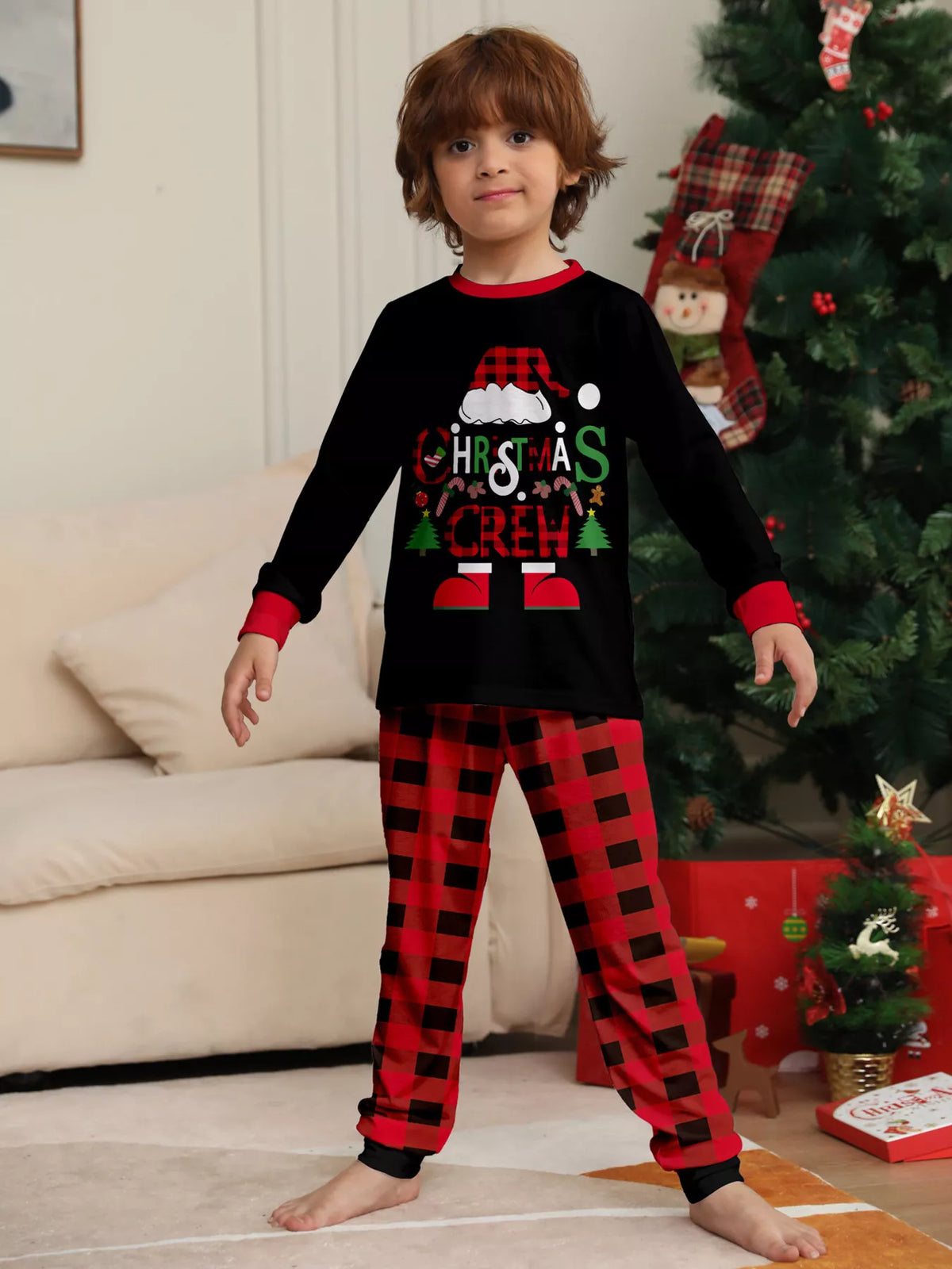 Child modeling the black Christmas graphic top and red plaid pajama pants.