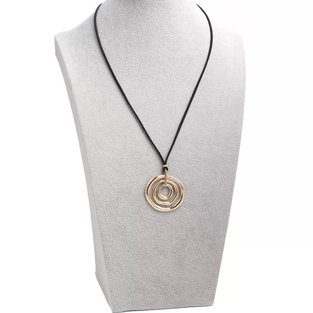 Long black cord necklace with a round gold-tone spiral pendant — detail view