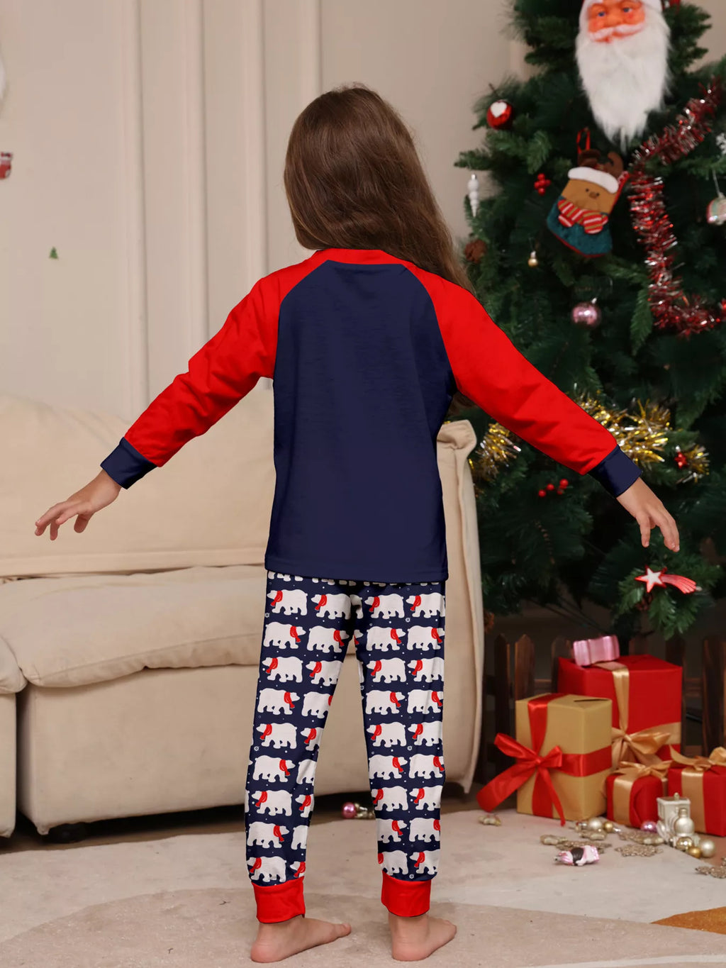 Navy and red Christmas graphic pajama top with matching festive-print pants worn by a child — back view