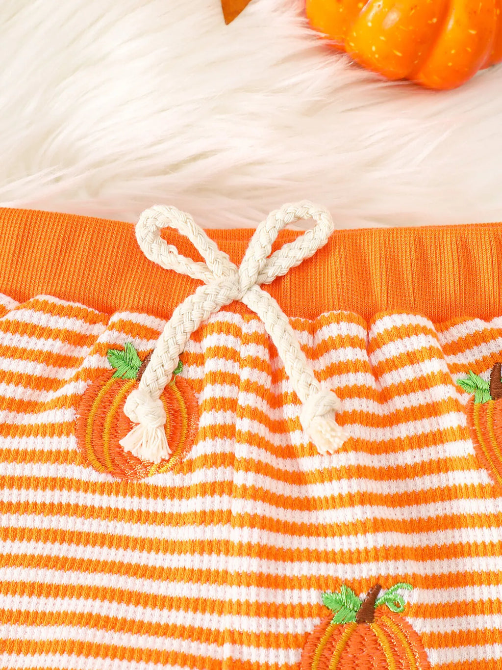 White drawstring waistband and pumpkin print on the orange-striped pants