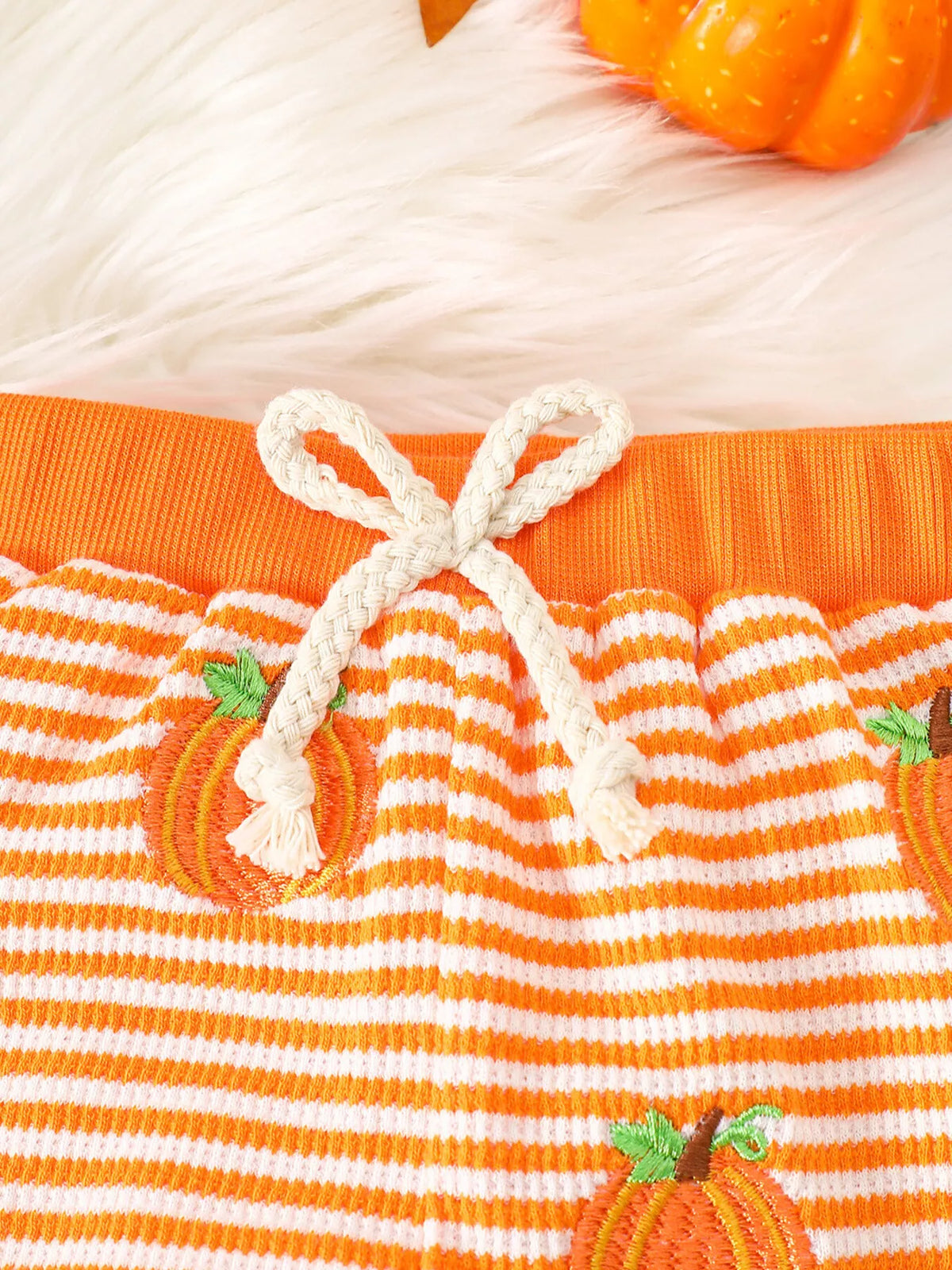 White drawstring waistband and pumpkin print on the orange-striped pants
