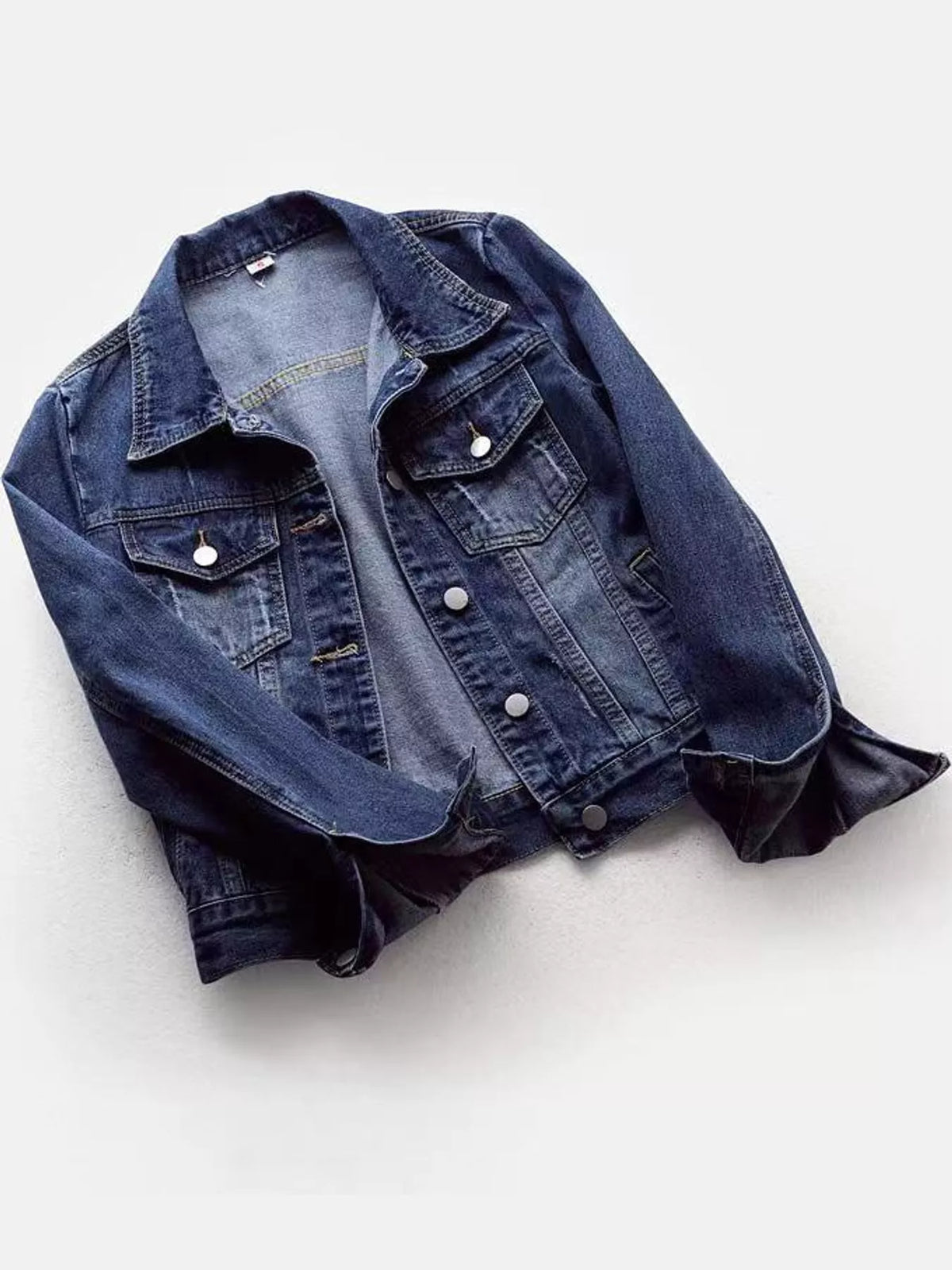 Medium-wash button-front denim jacket displayed with rolled cuffs.
