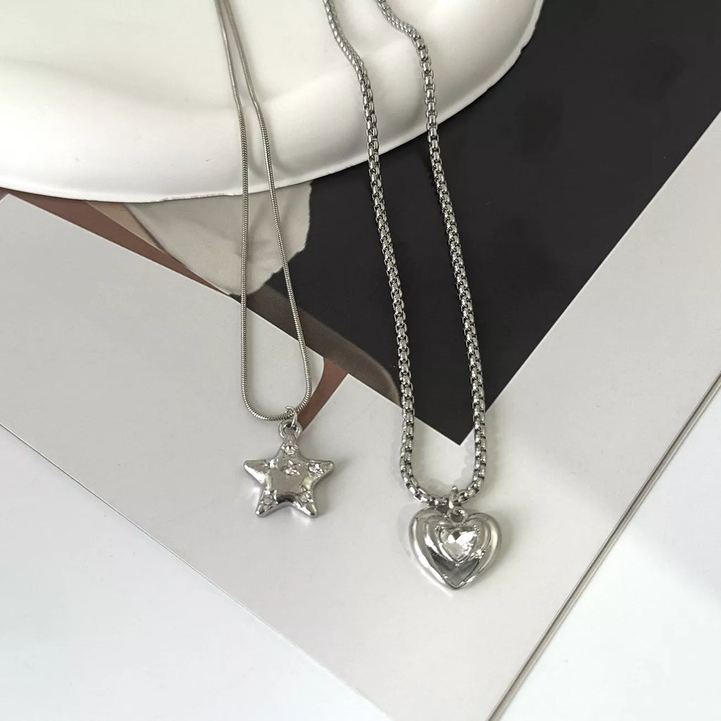 Layered silver-tone star and heart pendant necklaces — detail view