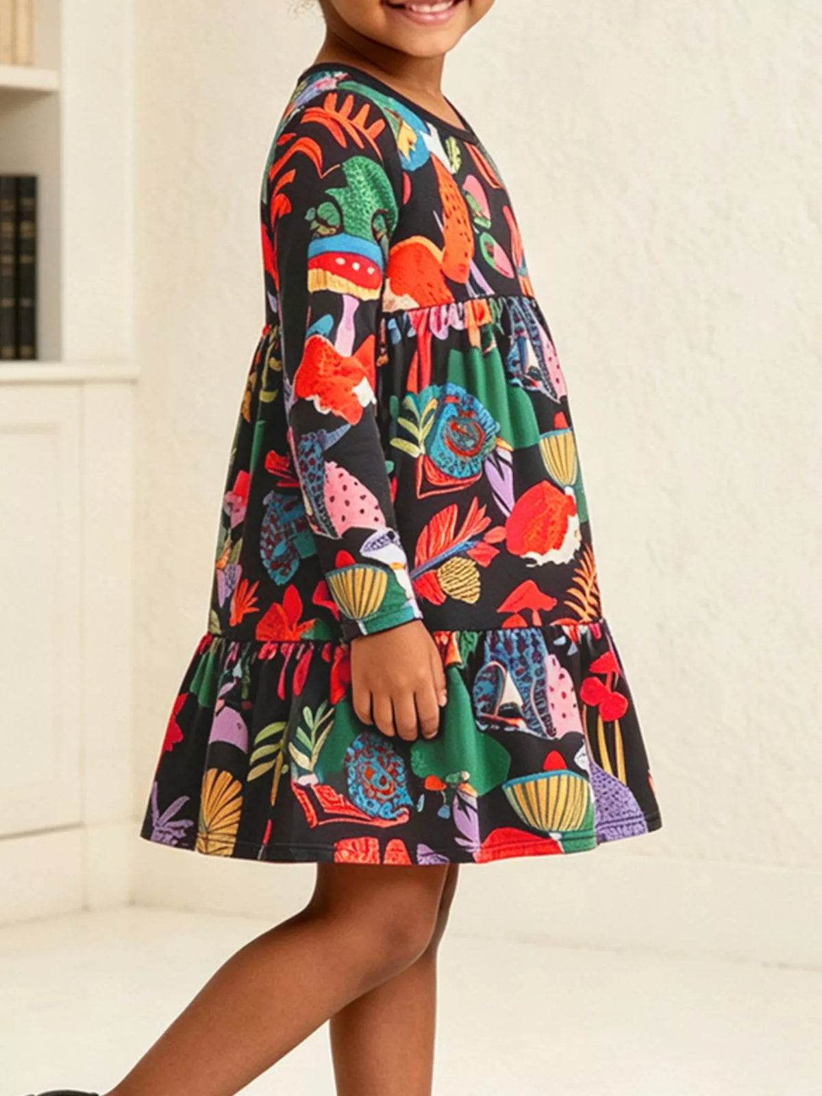 Side view of the child's colorful botanical-print tiered dress.