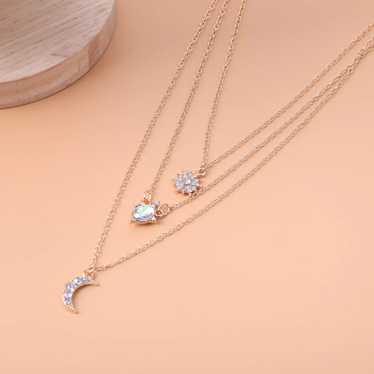 Layered silver-tone necklace with celestial and clear stone charms — detail view