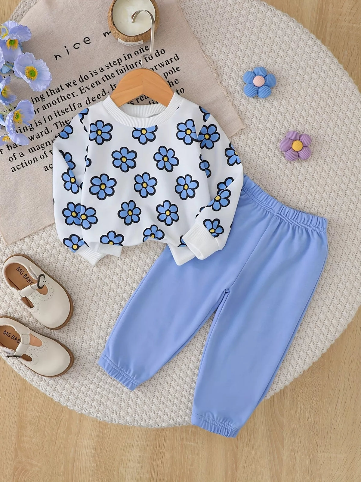 Flat lay of a white blue-flower sweatshirt and light blue jogger pants.