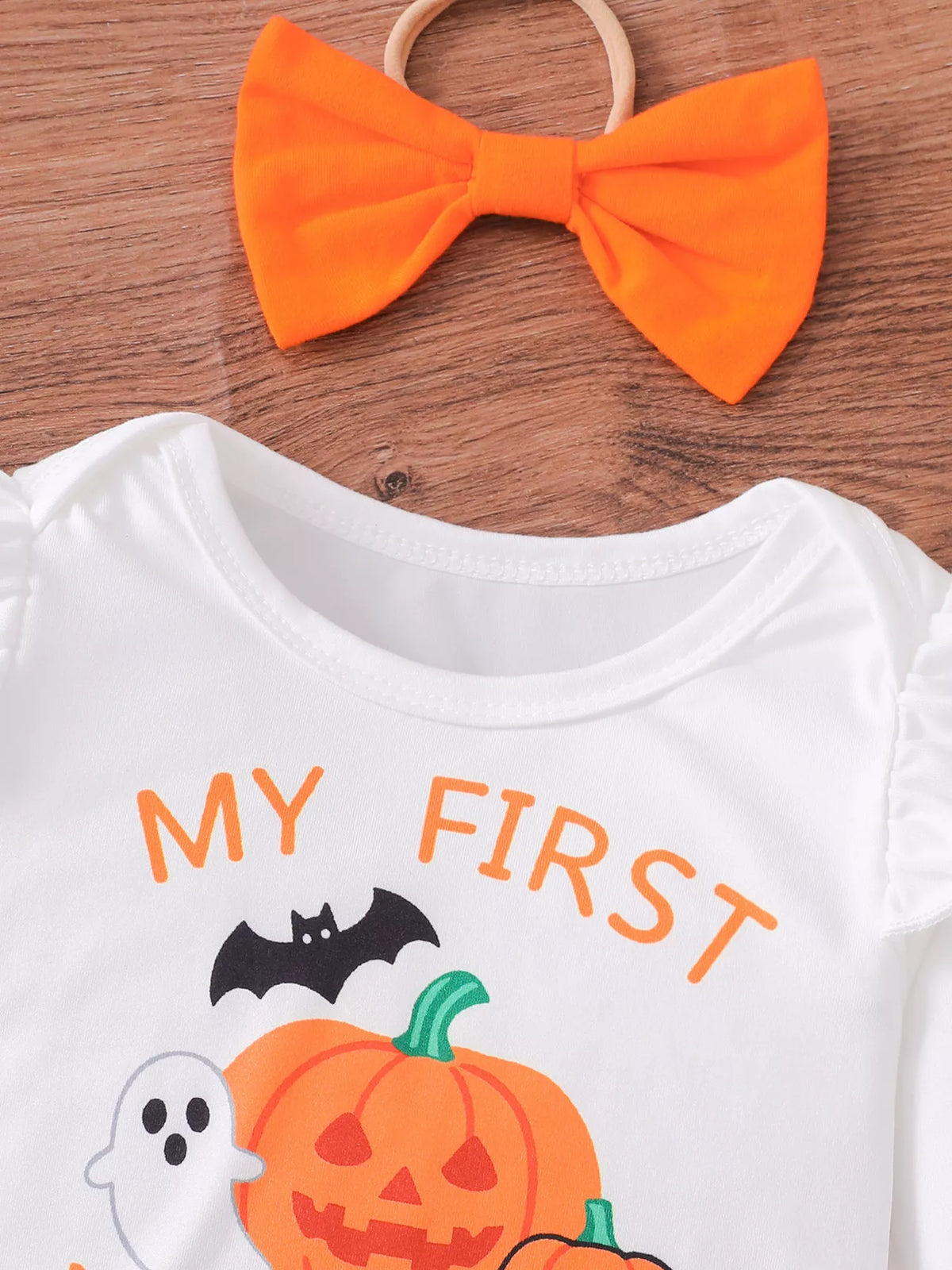 Close-up of the white My First Halloween bodysuit neckline and matching orange bow.