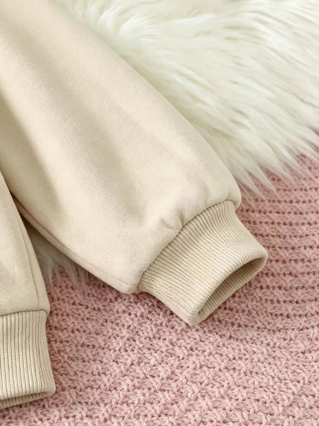 Close-up of the cream sweatshirt's ribbed sleeve cuff.