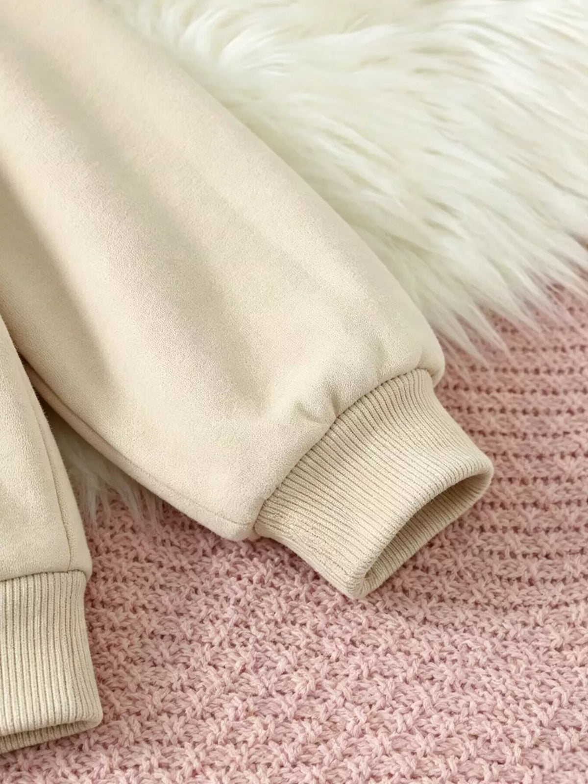 Close-up of the cream sweatshirt's ribbed sleeve cuff.