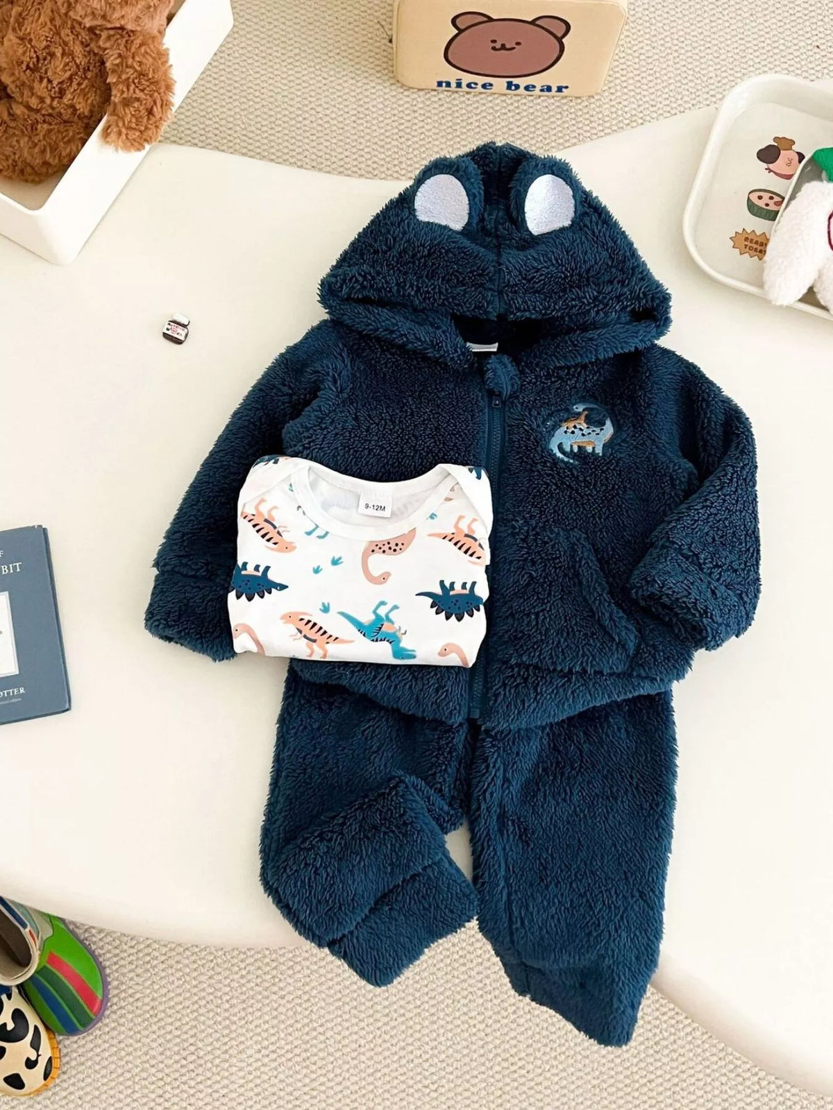 Children’s navy dinosaur fleece hoodie and pants with a white dinosaur-print bodysuit displayed flat