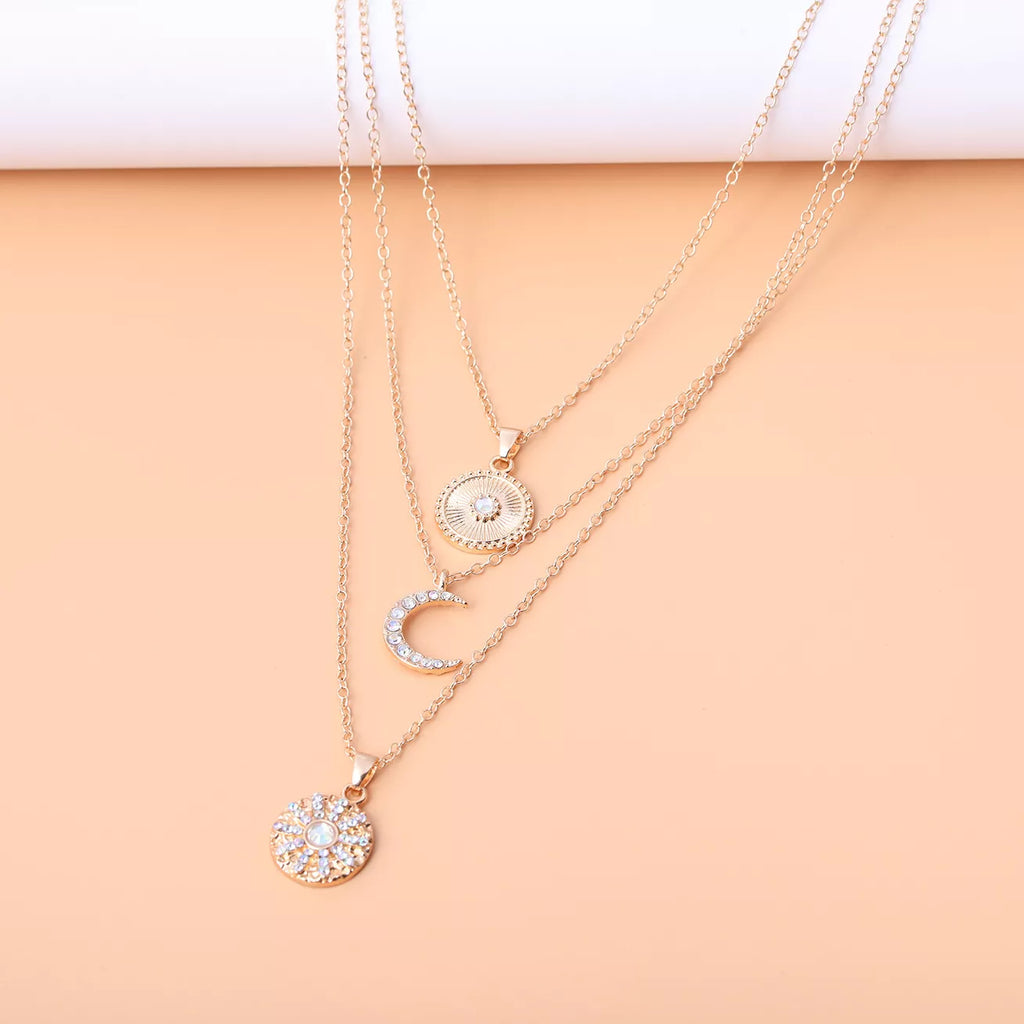 Layered gold-tone moon and coin pendant necklace — detail view