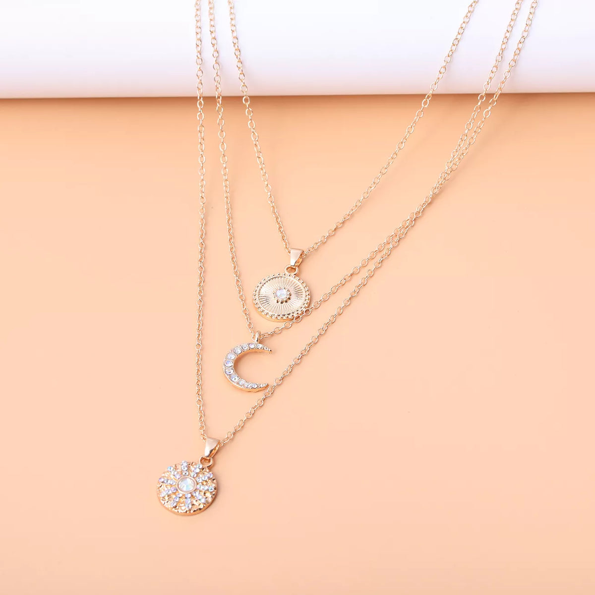 Layered gold-tone moon and coin pendant necklace — detail view