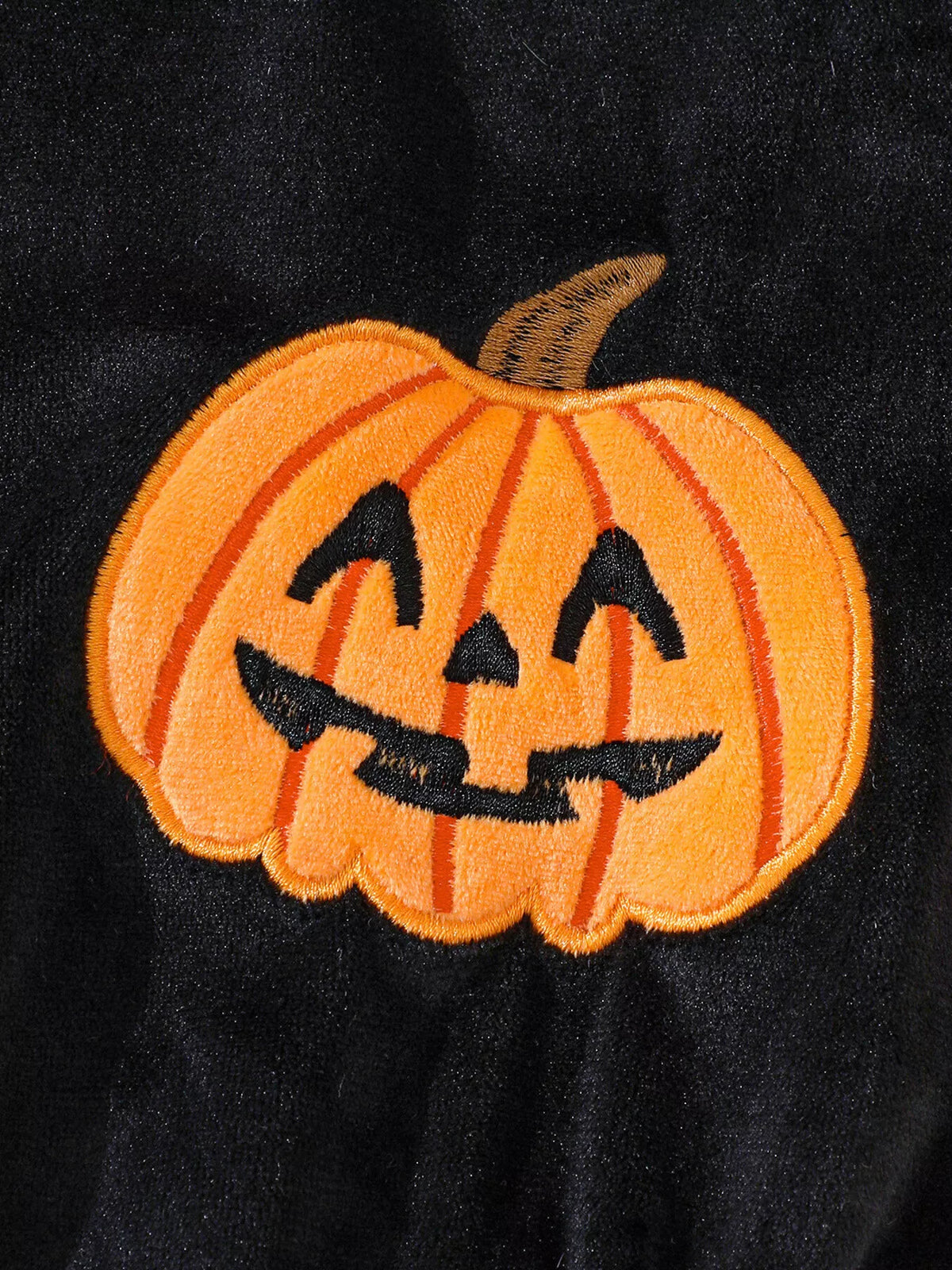 Orange jack-o’-lantern applique on the black baby bodysuit