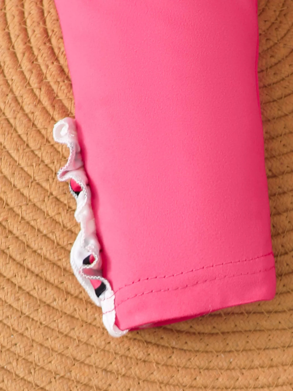 Close-up of the bright pink leggings' hem stitching and floral trim.