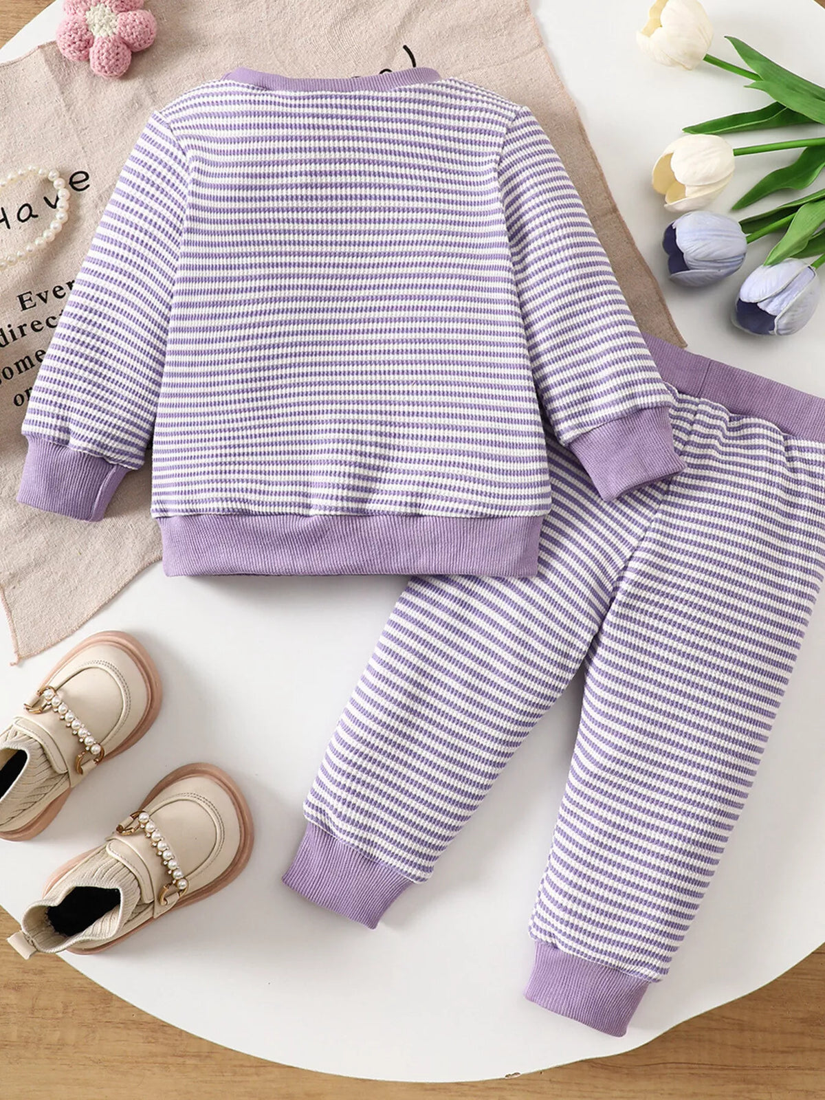 Purple striped ghost graphic pajama top and matching pants displayed flat