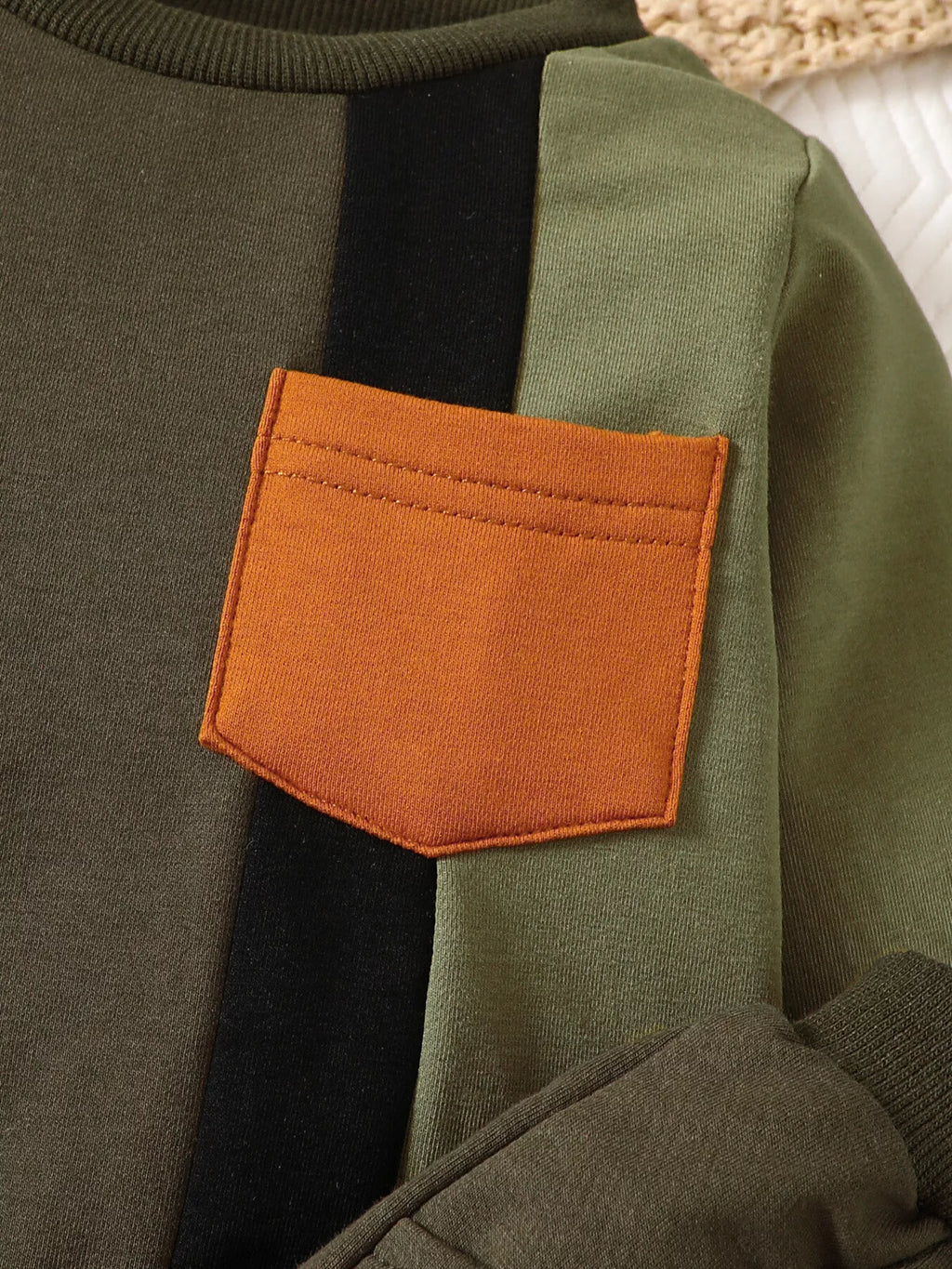 Orange patch pocket and black panel on the olive color-block sweatshirt
