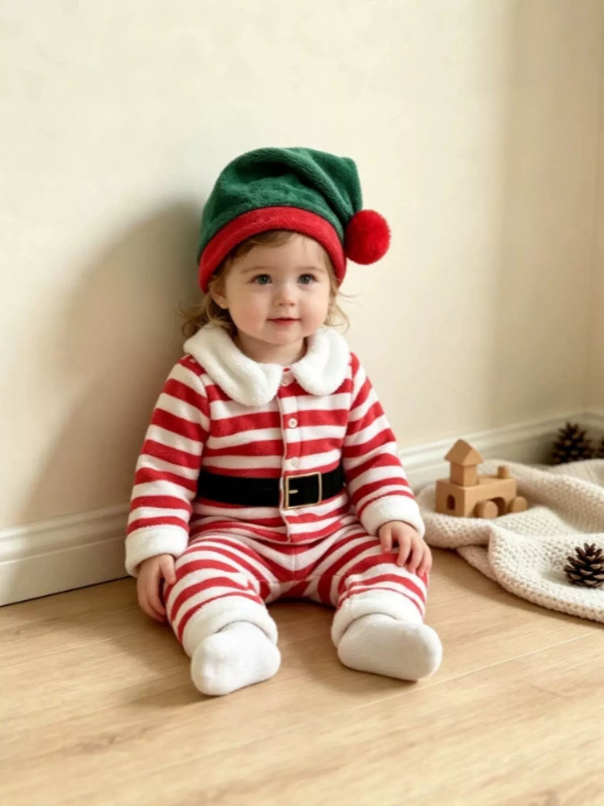 Red and white striped Christmas pajamas with printed black belt and green elf hat worn by a child
