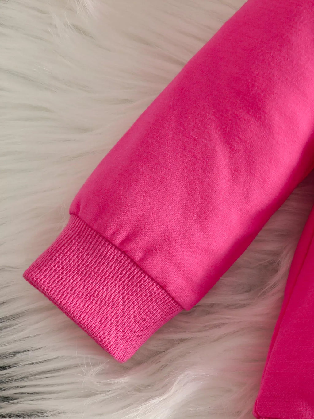 Close-up of the bright pink top's ribbed sleeve cuff.