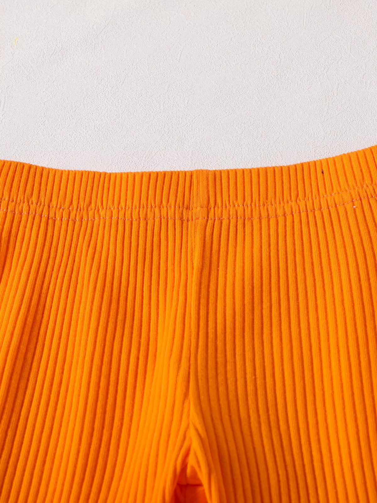 Close-up of the orange ribbed pants' waistband.